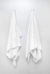 Fototapeta premium Two white towels hanging on hooks in bathroom, cleanliness and hygiene concept
