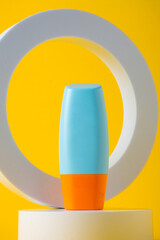 Cosmetic product in tube, bottle, lotion or serum with stylish props on yellow background. 