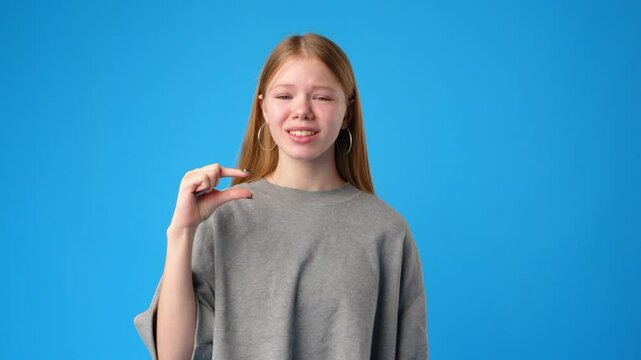 Young girl communicates using sign language in front of a bright blue background during a tutorial session