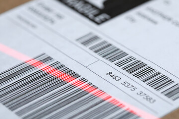 Parcel with label, closeup. Red laser light on barcode for scanning