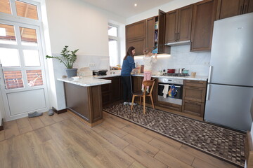 Mother and a child girl cooking and eating indoors together 
