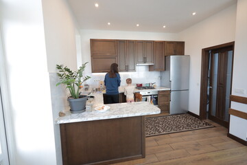 Mother and a child girl cooking and eating indoors together 
