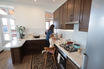 Mother and a child girl cooking and eating indoors together 