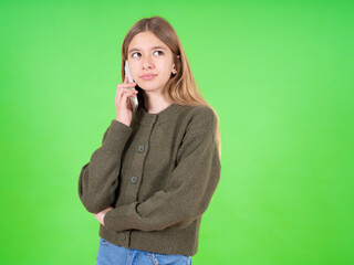 Fototapeta premium Sad beautiful caucasian girl wearing green sweater talking on smartphone. Communication concept.