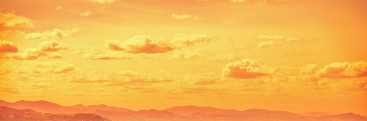 Cloudy sky over mountains at golden sunset. Abstract nature background. Basque country, Spain. Horizontal banner