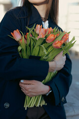 Unrecognizable cropped woman holding tulip flowers at the city street