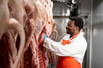 Experienced meat industry worker preparing pork meat in slaughterhouse for food processing.
