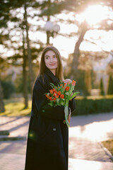 Fototapeta premium Happy woman holding a tulip flowers at spring day