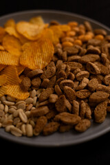 plate with beer snacks on black background