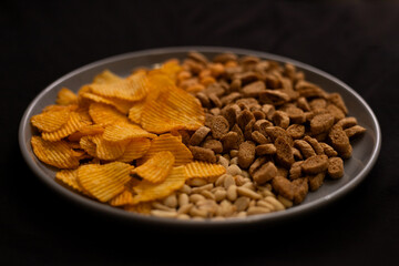 plate with beer snacks on black background