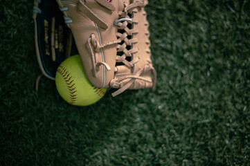 softball in a baseball glove close up, selective focus background image, synthetic grass, training facility
