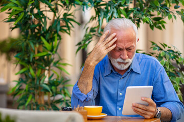Senior Man Engaged With Tablet Amidst Outdoor Cafe Setting