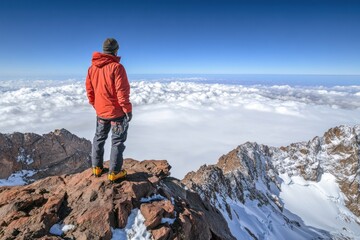 Fototapeta premium Climber atop mountain peak, gazing at cloudscape