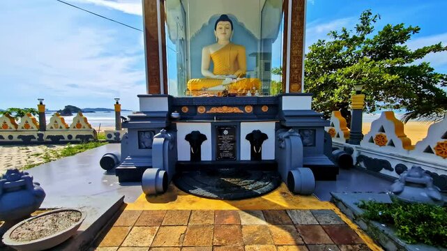 A serene Buddha statue encased in glass at a coastal shrine overlooking the ocean in Weligama, Sri Lanka