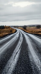 Naklejka premium Road stretching into the distance beneath a dramatic cloudy sky with hints of sunlight