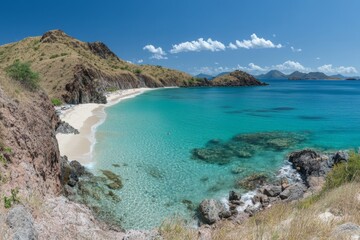 Obraz premium Serene tropical beach with crystal-clear water and rocky shoreline during bright sunny day in a coastal paradise