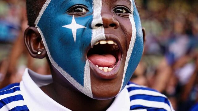 Excited child with Somali flag face paint cheering at a sports event  

