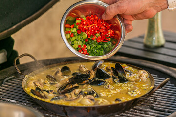 The chef prepares a traditional seafood paella on the grill.Traditional spanish dish. Fresh and Colorful Spanish Seafood Paella. Mediterranean cuisine and seafood dishes.