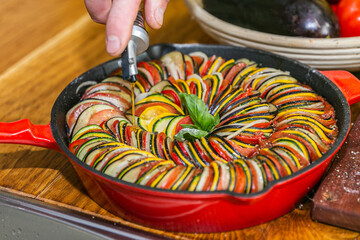 Chef preparing traditional Provençal vegetable dish Ratatouille with stuffed rolled meat on the grill. French food. Healthy eating. Delicious vegetable
