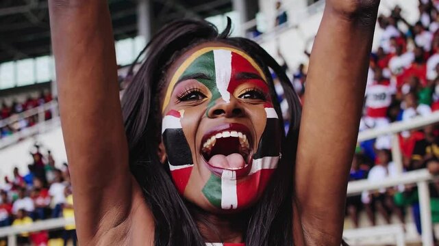 Cheerful Sudanese sports fan with artistic flag face paint at a stadium event  
