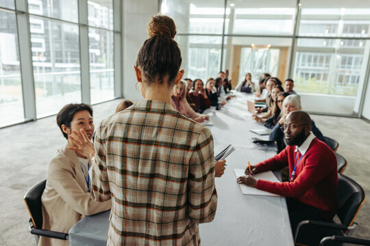 Female leader conducting workshop with professionals in modern office setting, focusing on collaboration and innovation in business strategy meeting