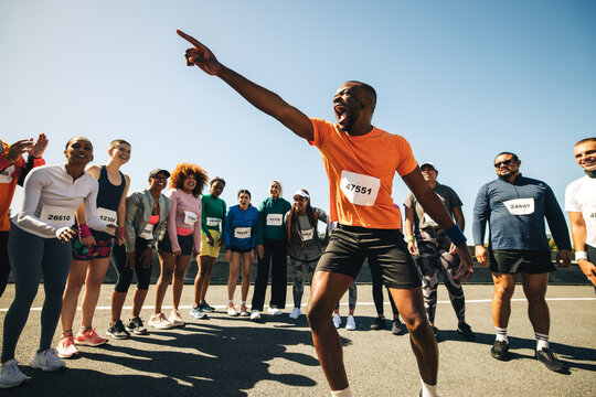Energetic running coach hyping up diverse group before a race - Powered by Adobe