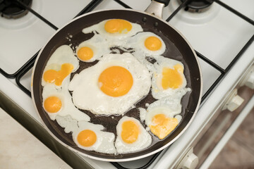 Chicken egg and 9 quail eggs in frying pan.