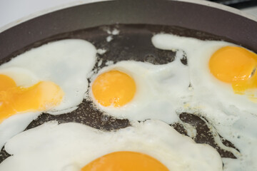 Chicken egg and 9 quail eggs in frying pan.