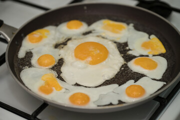 Chicken egg and 9 quail eggs in frying pan.