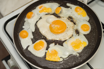 Chicken egg and 9 quail eggs in frying pan.