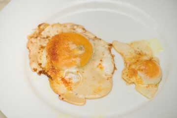 Chicken egg and 9 quail eggs in frying pan.