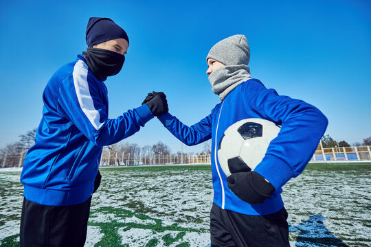 Young football players greeting each other with handshake before match, symbolizing friendship and sportsmanship. Concept of sport, childhood, teamwork, motivation, discipline, active lifestyle. - Powered by Adobe