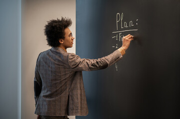 Curly-haired businessman doing business planning and writing on the board
