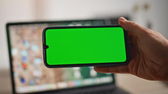 Hand holding horizontal mockup cellphone at workplace closeup. Unknown man 