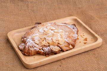 almond croissants on wooden cutting board on white marble background