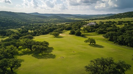 Obraz premium Scenic Aerial View of Rolling Hills and a Grand Estate with Lush Green Pastures under a Cloudy Sky