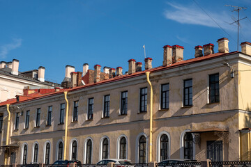 Obraz premium Historic architecture of Saint Petersburg with yellow facade and red roofs against a clear blue sky