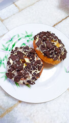 Two chocolate Oreo donuts on a white plate