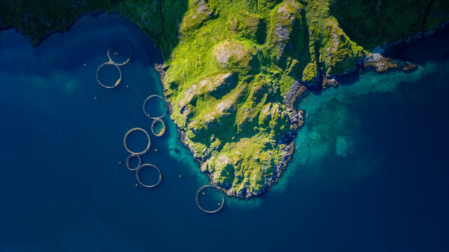 Aerial view of a panoramic salmon farm with fish pens in a beautiful coastal landscape, Kamoyvaer, Mageroy Island, Finnmark, Norway.