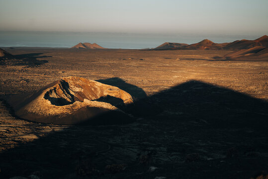 Aerial view of a breathtaking volcanic landscape with majestic rock formations and shadows at sunset, Fuente de Montana Negra, Lanzarote, Canary Islands, Spain.