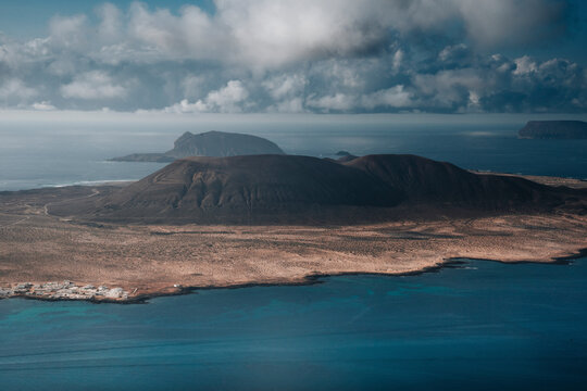 Aerial view of volcanic island landscape with rugged terrain and serene ocean, Las Hoyas, Lanzarote, Canary Islands, Spain.
