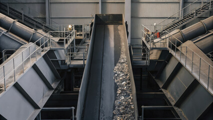view of waste processing facility with conveyor belt transporting refuse. industrial setting highlights importance of waste management and recycling efforts