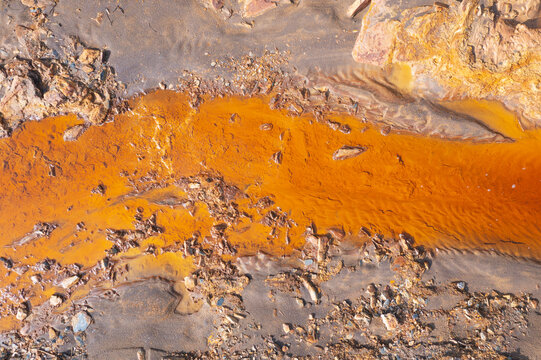 Aerial view of the vibrant orange water of Rio Tinto with striking geological formations and rugged terrain, Minas de Riotinto, provincia de Huelva, Spain.