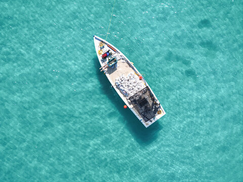Aerial view of dhonis and sand pickers on a beautiful tropical beach with turquoise clear water, Vashafaru, Haa Alif Atoll, Maldives.