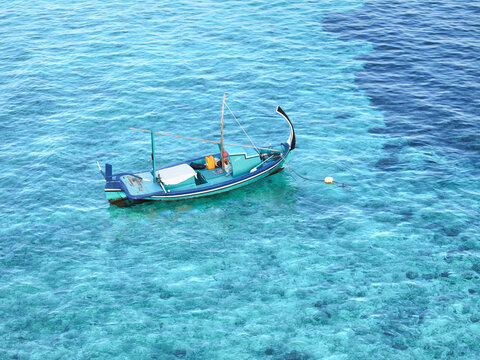 Aerial view of a traditional dhoni boat surrounded by vibrant corals and crystal clear turquoise water, Vashafaru, Haa Alif Atoll, Maldives.