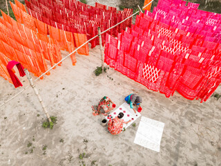 Narayanganj, Bangladesh - 12 October 2024: Aerial view of vibrant hand-dye fabrics drying in the sun at a factory field, Narayanganj, Dhaka, Bangladesh.
