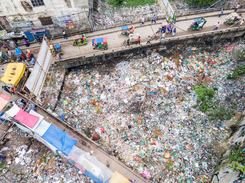 Aerial view of a polluted river surrounded by bustling urban infrastructure and daily business activities, Aganagar, Keraniganj, Dhaka, Bangladesh.