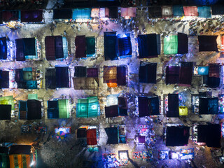 Aerial view of vibrant night market with colorful stalls and illuminated tents bustling with people, Tongi, Gazipur, Bangladesh.