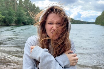 young girl suffers from cold, wind in nature