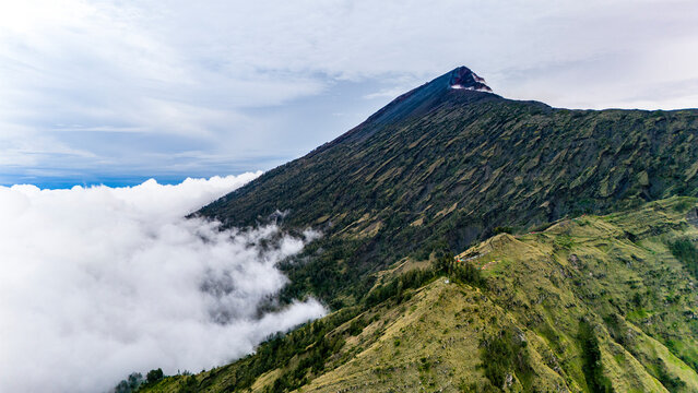 Aerial drone view of the top of active Rinjani volcano above the clouds, island of Lombok, Indonesia